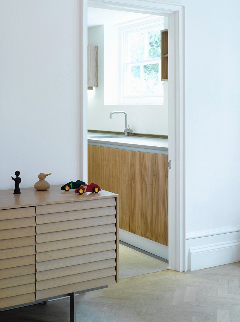 Modern sideboard with overlapping slatted front next to an open kitchen door