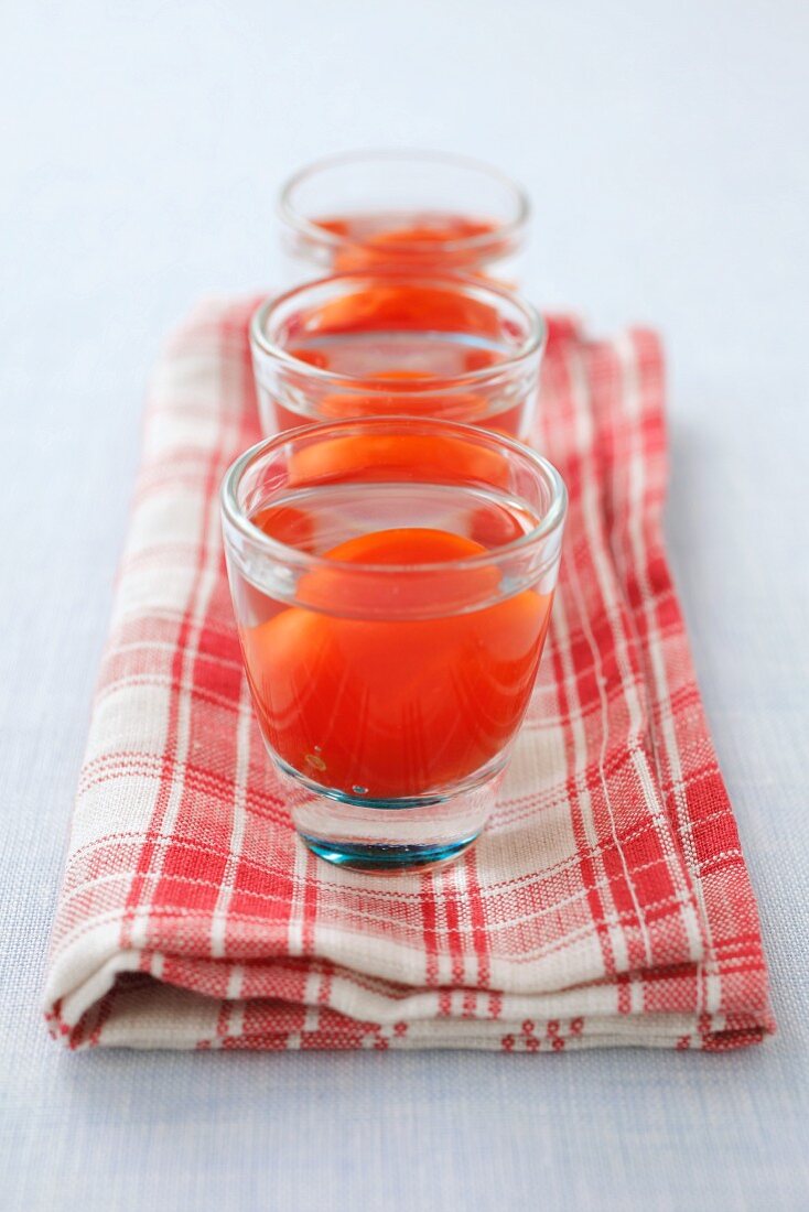 Shot glasses filled with vodka and cherry tomatoes