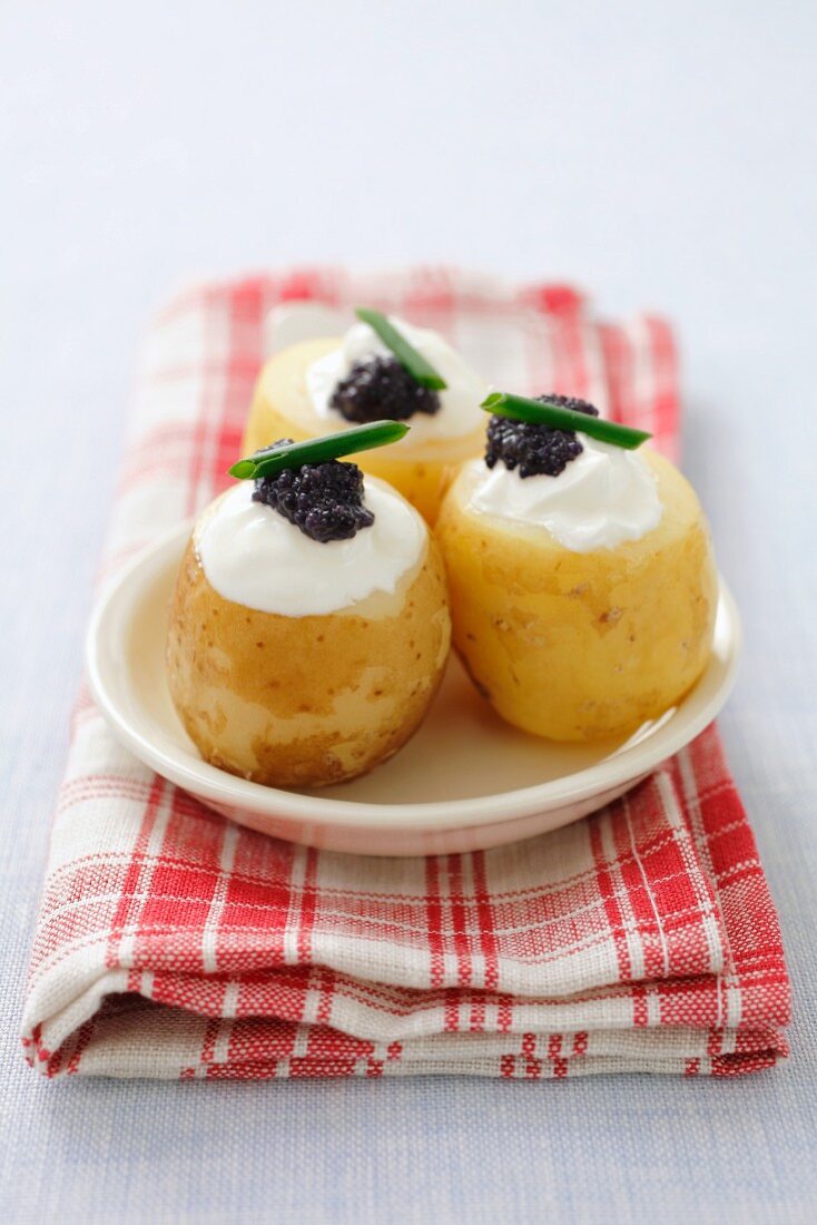 Potatoes topped with cream cheese and caviar
