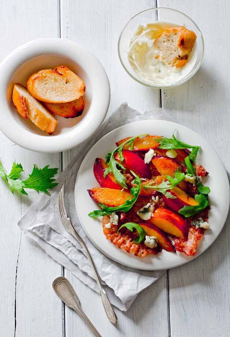 A salad made with roasted peaches, bacon, blue cheese, walnuts and rocket with toasted bread