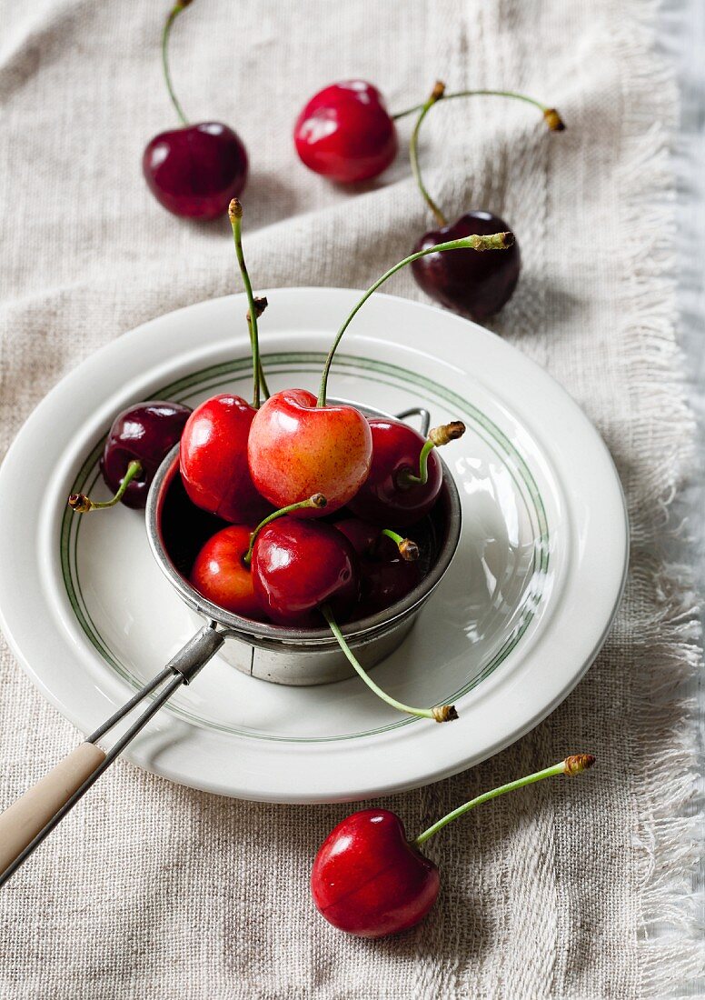 Sour cherries in a tea strainer on a plate