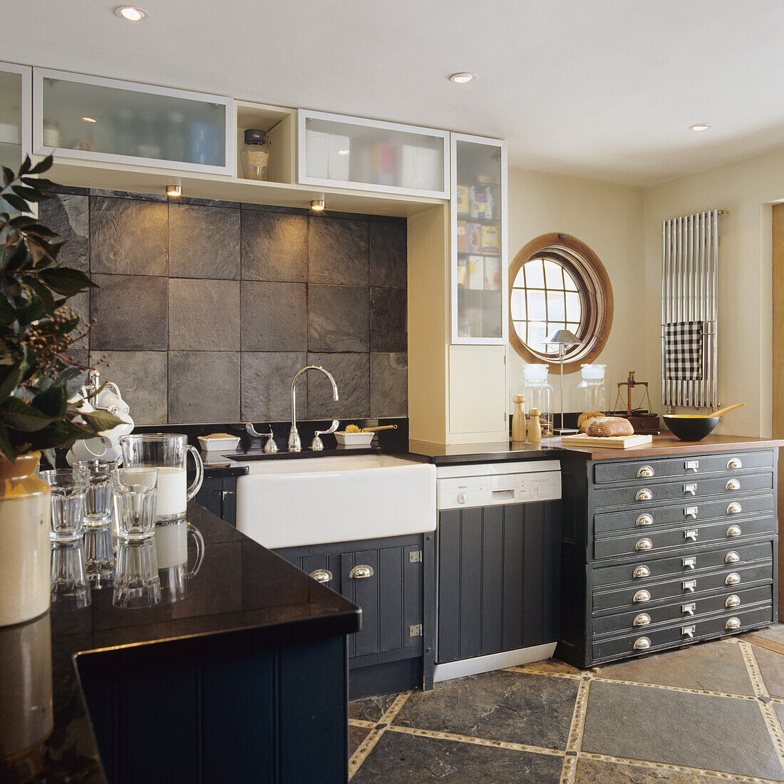 Kitchen with dark fronts, country-style sink and natural stone tiles