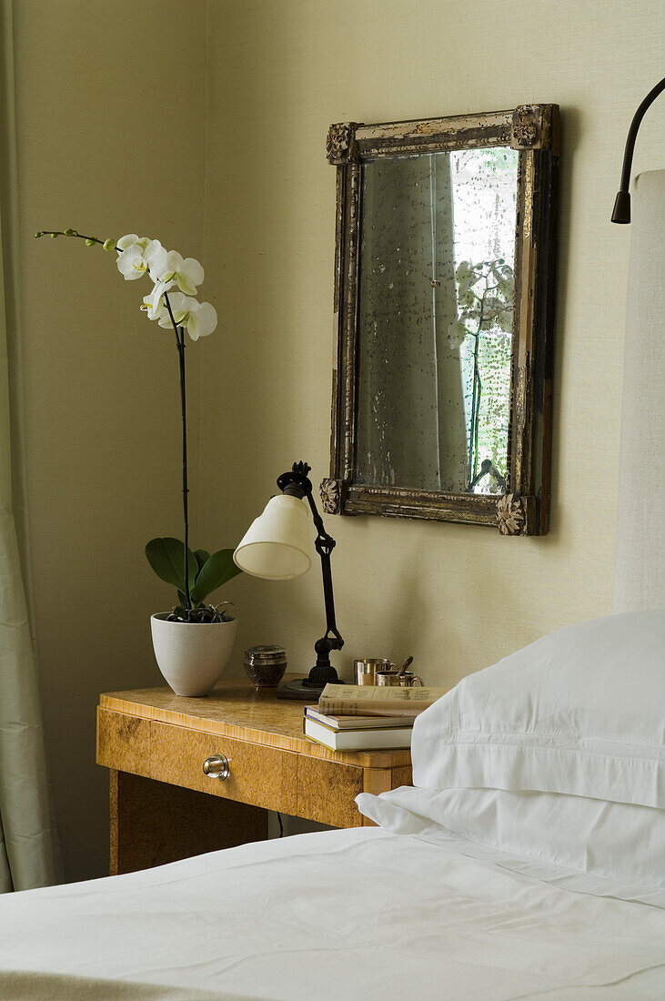 Wooden bedside table with orchid and antique mirror in the bedroom