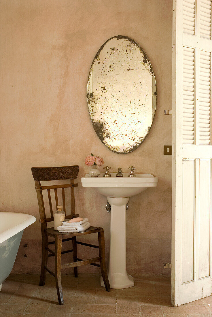 Wooden chair and antique oval mirror in the vintage bathroom