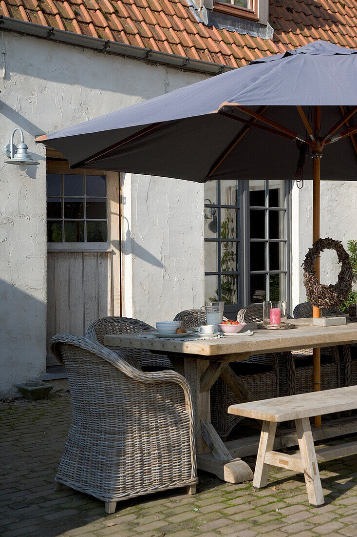 Covered garden table with parasol in the morning sun