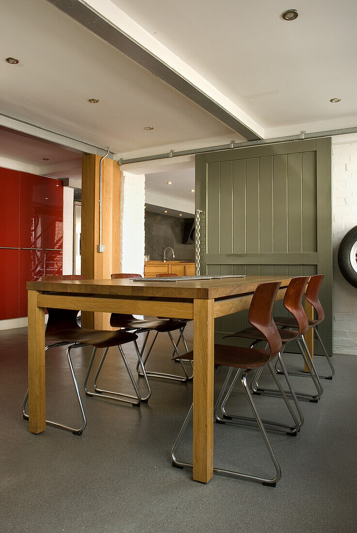 Modern kitchen with wooden dining table and metal chairs in front of olive green sliding door