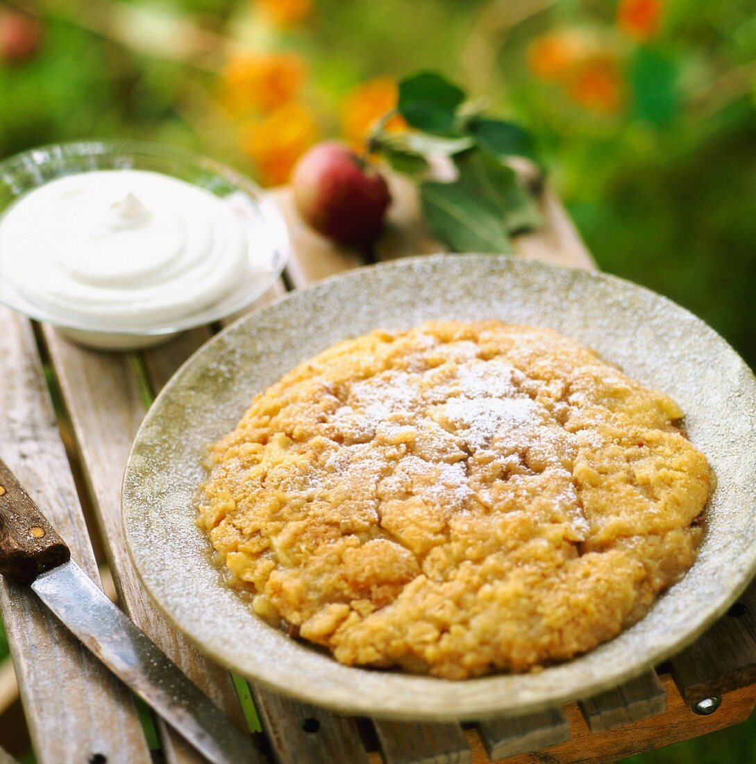 Apple pie with cream on a garden table