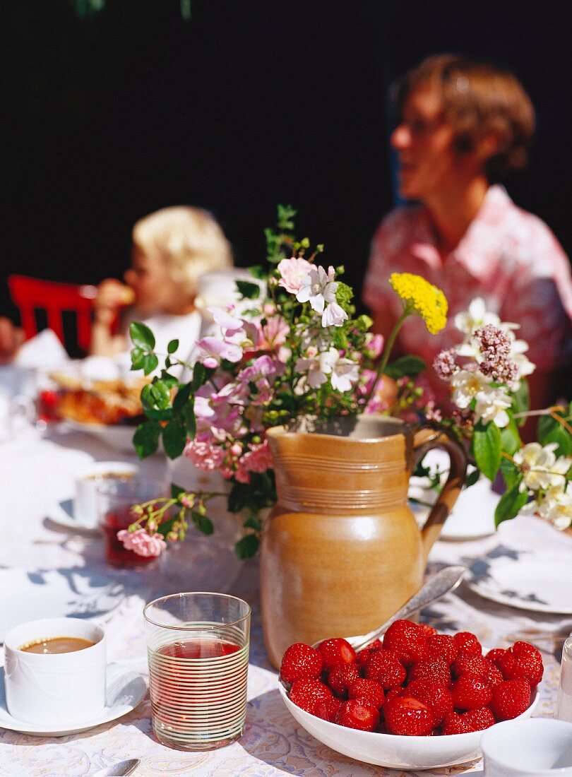 Sommerlicher Tisch mit Erdbeeren und Blumen
