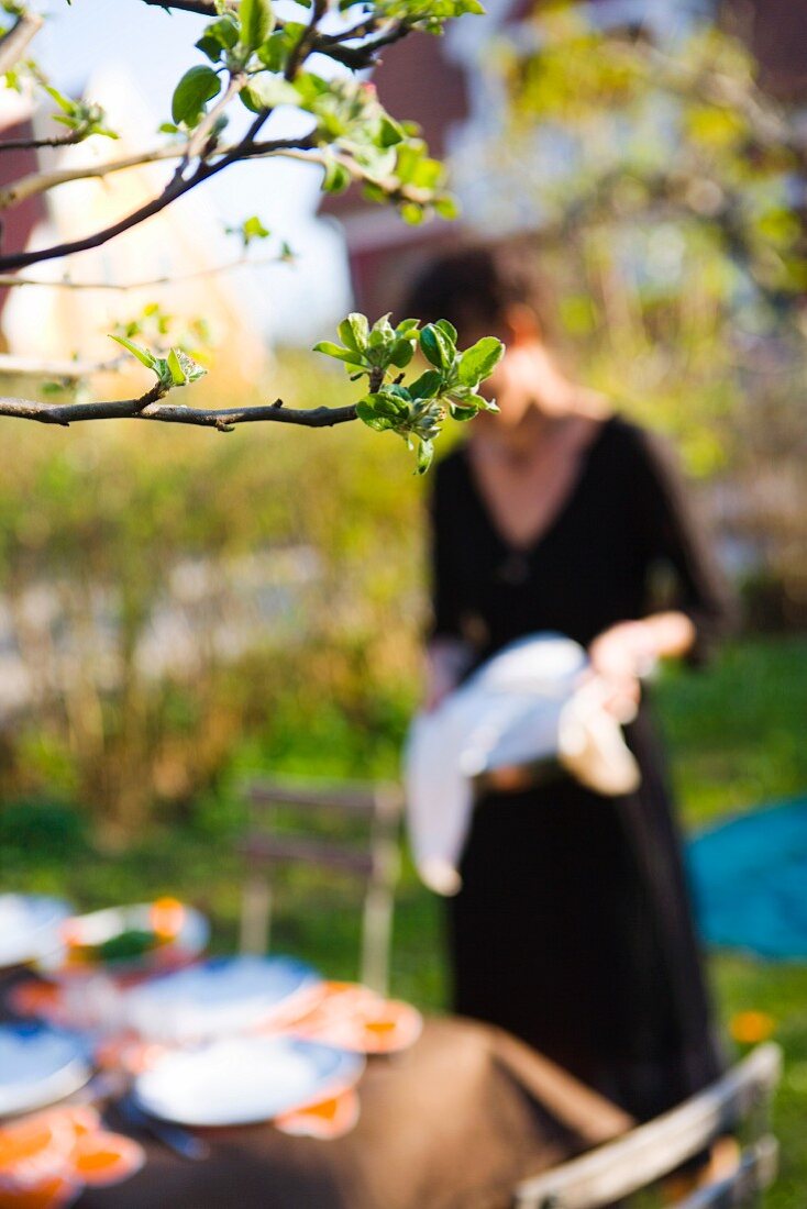 Frau geht zu gedecktem Tisch im Garten