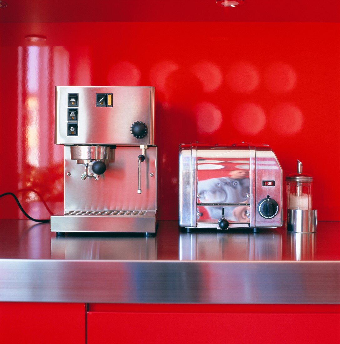 Espressomaschine und Toaster auf Edelstahlarbeitsfläche in leuchtend roter Küche