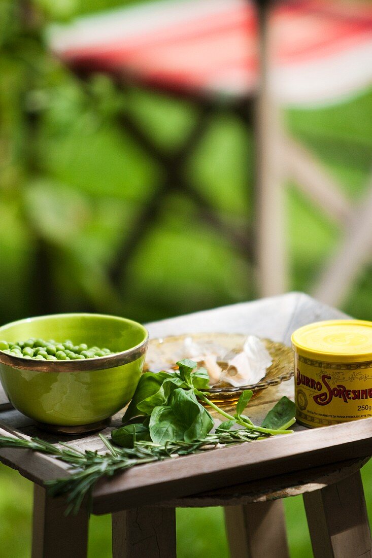 Butter, Erbsen und Kräuter auf Gartentisch