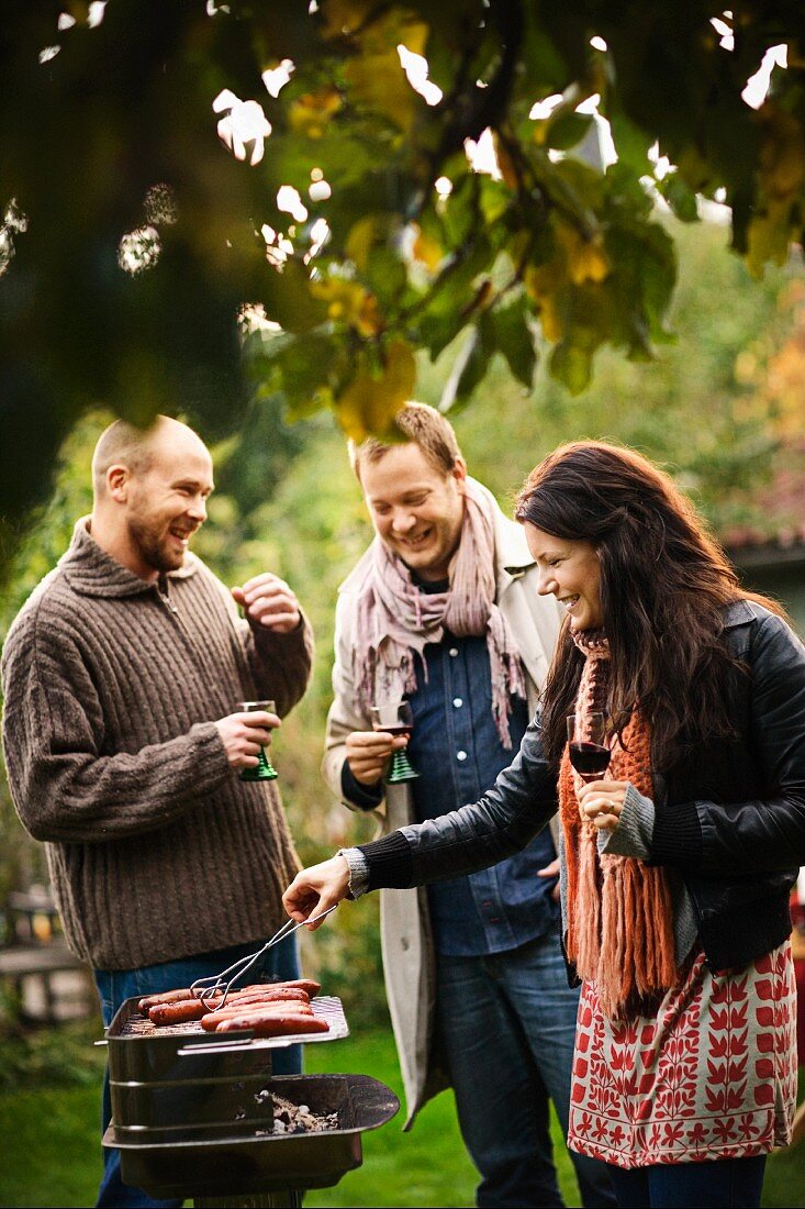 Freunde grillen Würstchen im Garten