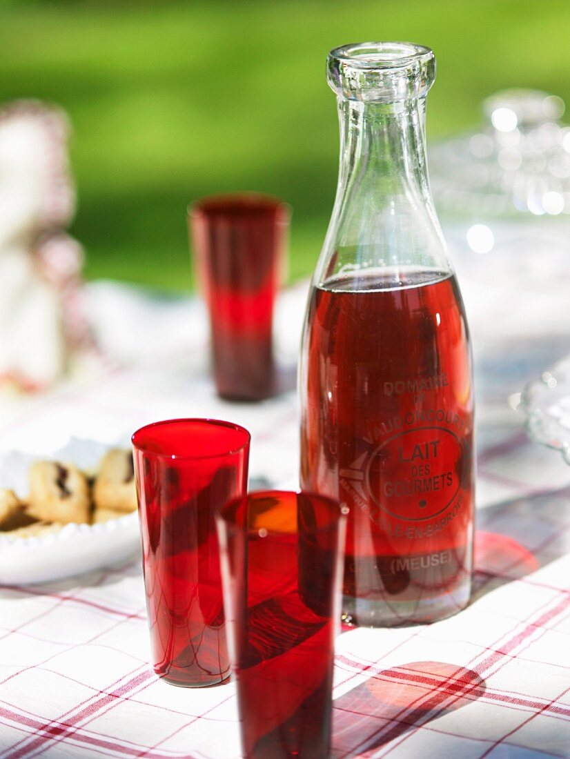 Selbstgemachter Fruchtsaft, rote Trinkglaser und Plätzchen