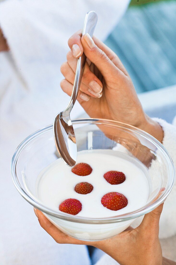 Frau isst Joghurt mit Erdbeeren