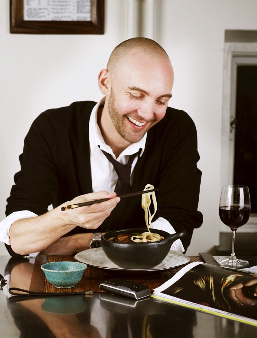 A man eating an Oriental noodle dish