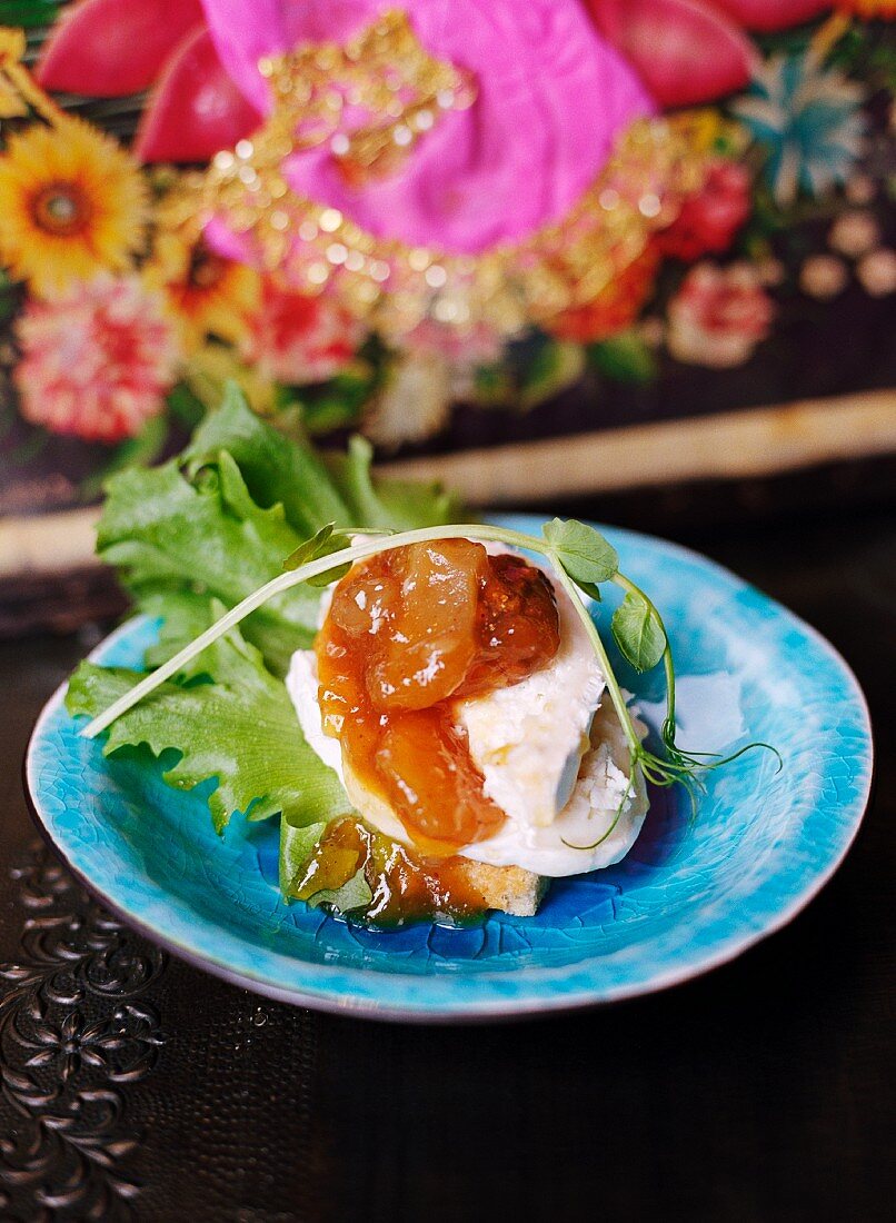 A slice of bread topped with goat's cheese, chutney and walnuts