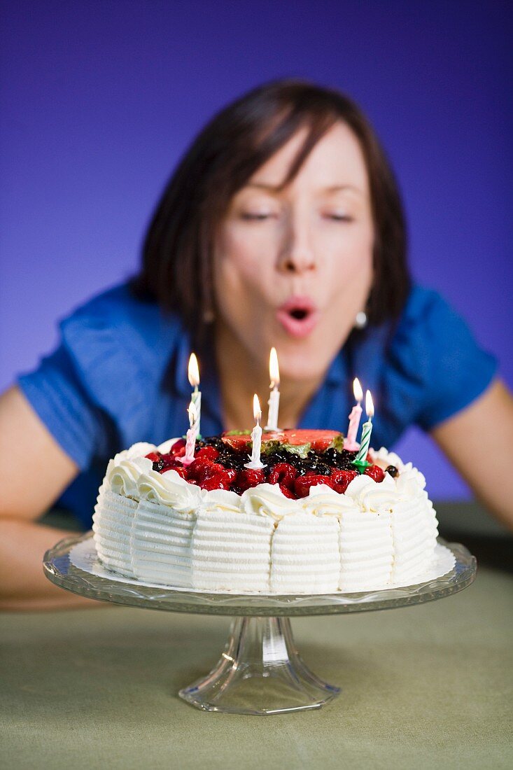 A woman blowing out candles on a birthday cake