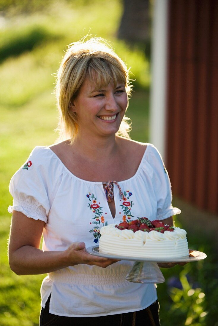 A woman serving a strawberry cake in a garden