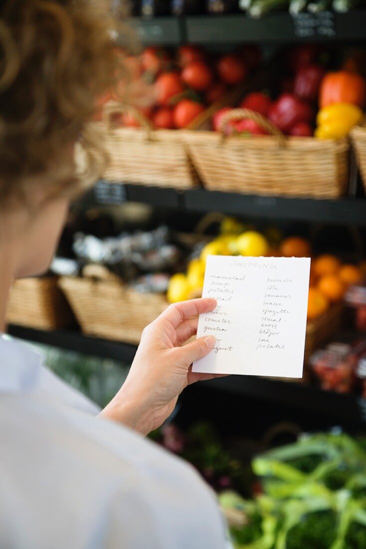 Frau mit Einkaufsliste im Supermarkt