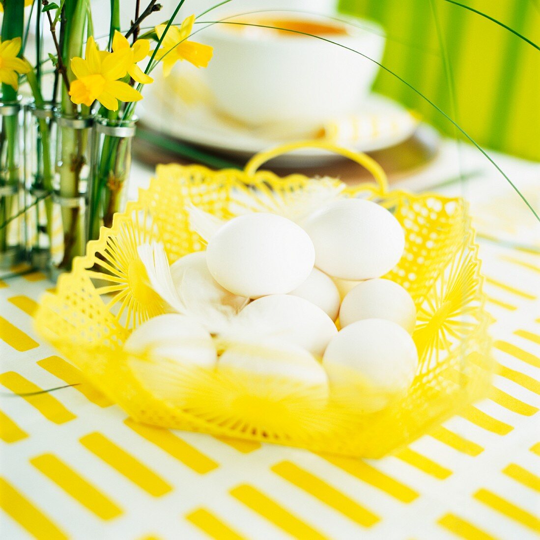 A table laid for Easter decorated with a basket of eggs and daffodils
