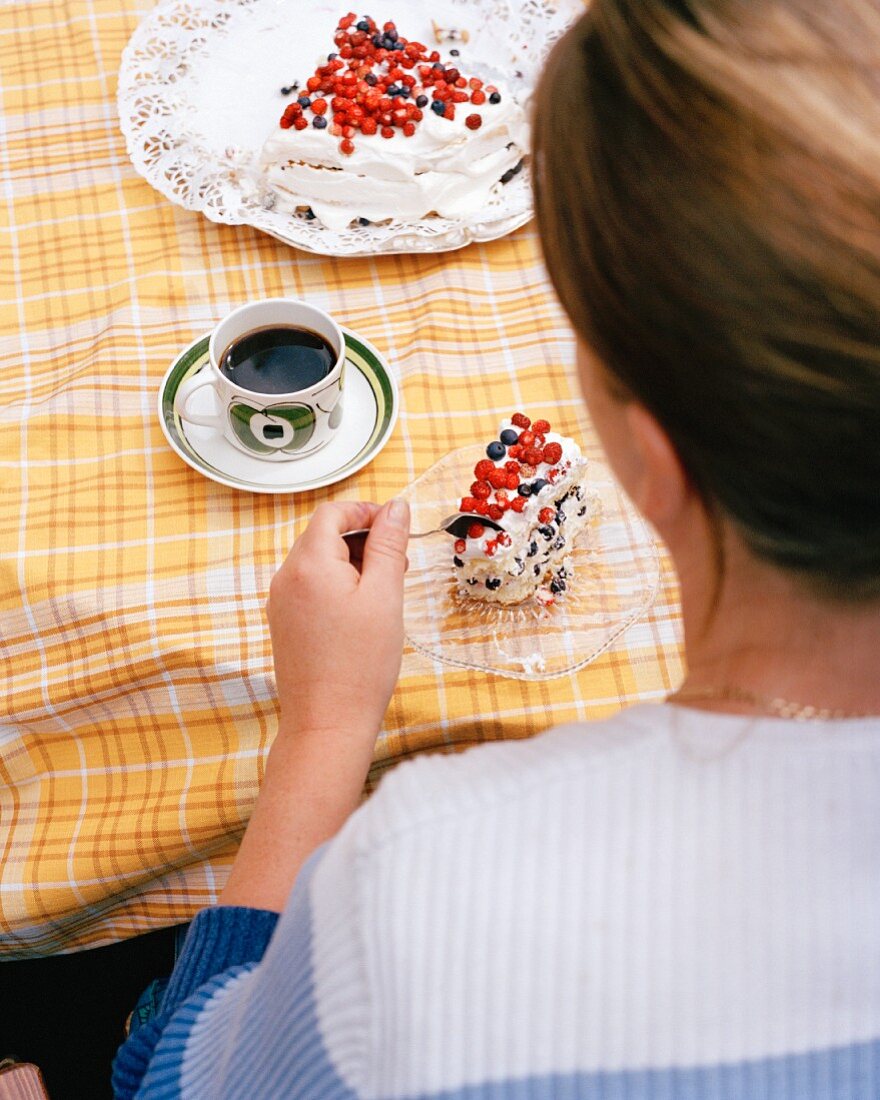 A woman eating a berry cake with coffee