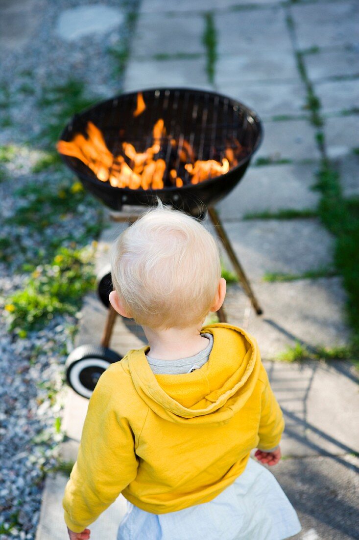 A little girl looking at a barbecue