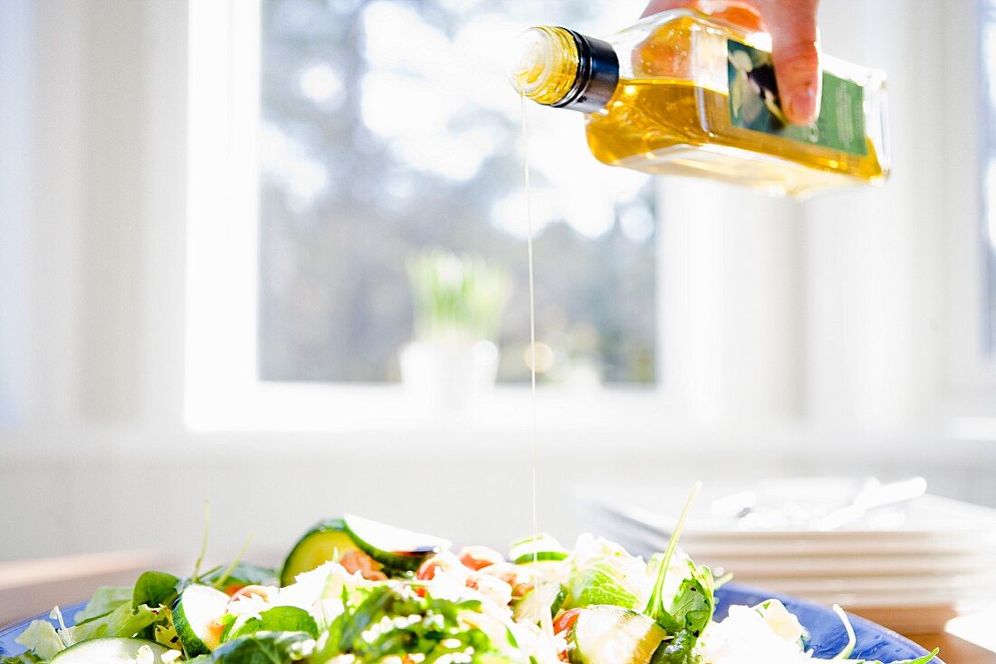 Olive oil being poured on salad