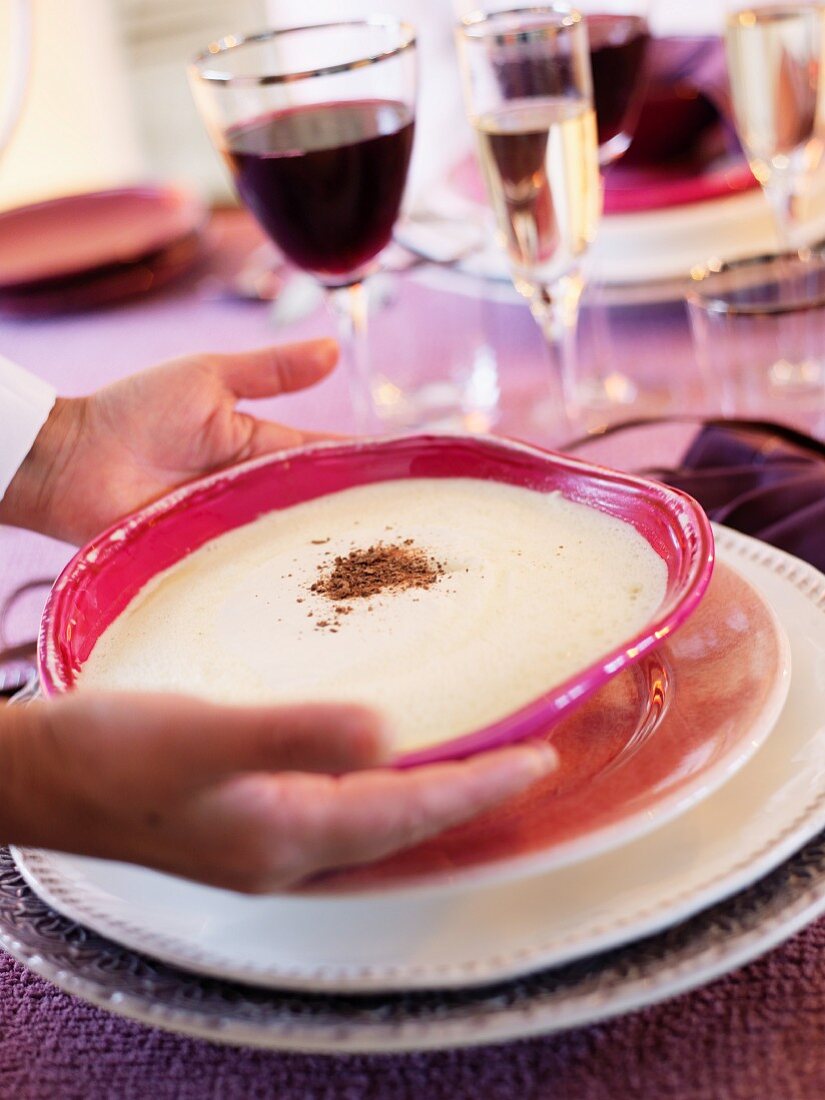 A person placing a dessert on a table