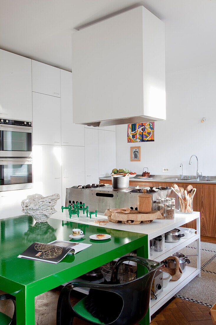 Modern kitchenette with green dining table and stainless steel appliances