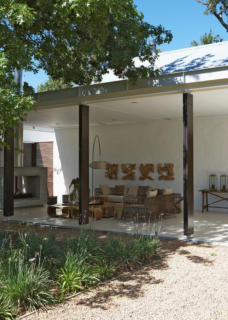 Contemporary house with comfortable patio furniture made from natural materials on roofed terrace