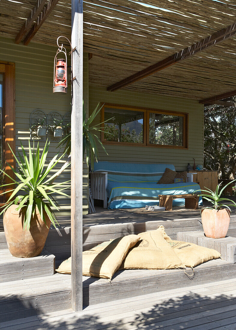 Terrassenbereich mit Holzdielen, Pflanzen in Terrakottatöpfen und Sitzplatz