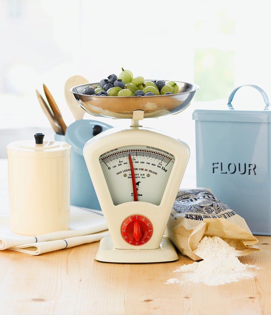 Berries on kitchen scales, baking ingredients and wooden spoons