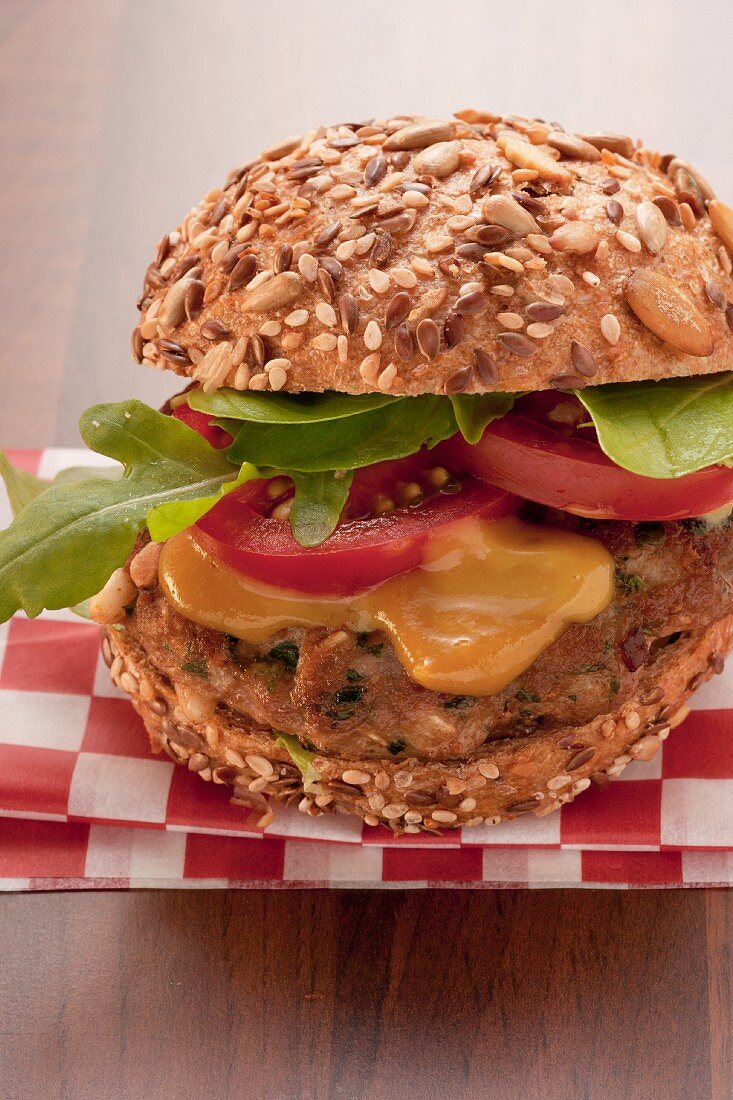 A burger with mustard, tomatoes and rocket