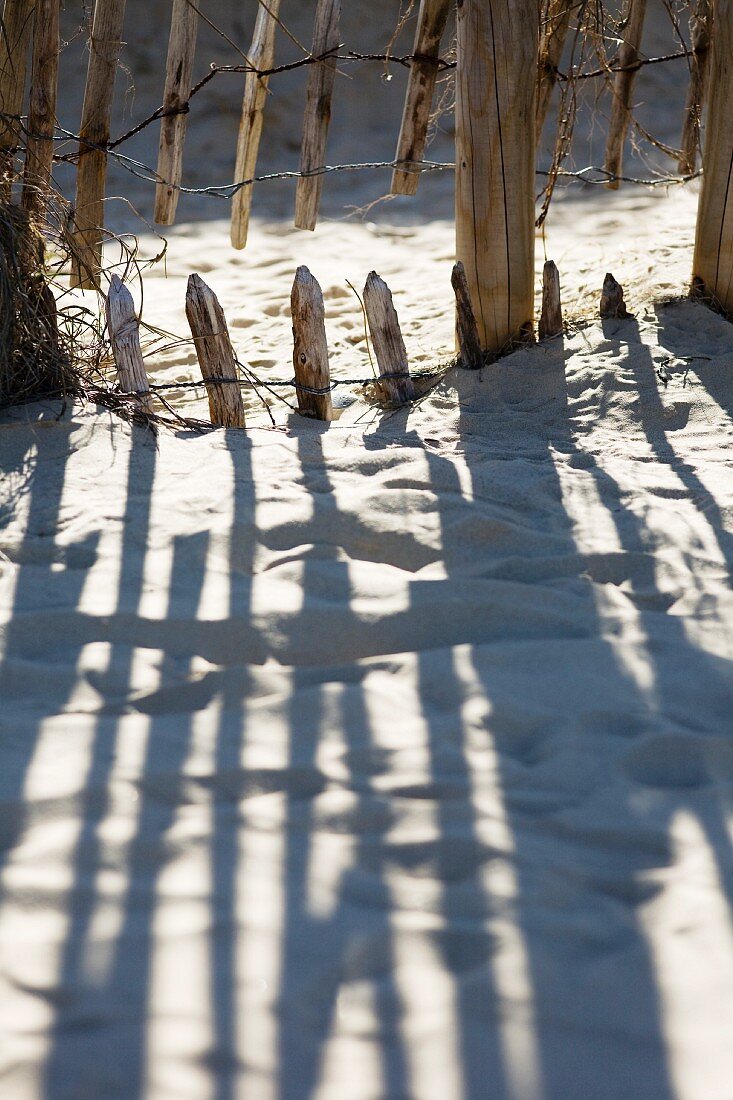 Shadow of wooden fence on sand