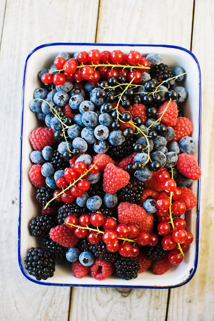 Various fresh berries in an enamel bowl