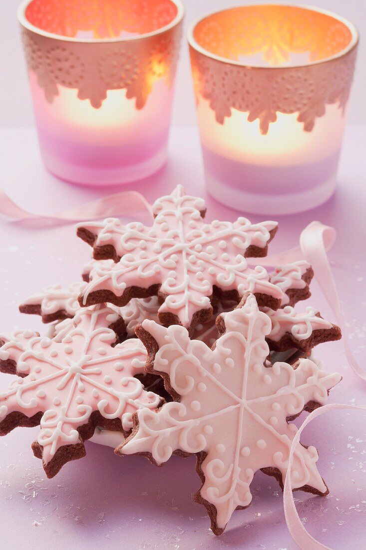 Star-shaped Christmas biscuits decorated with icing sugar with tealights in the background