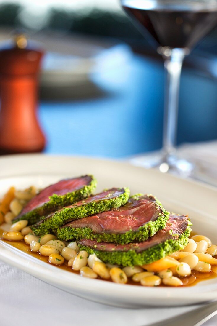 Sliced Herb Crusted Lamb Served Over White Beans