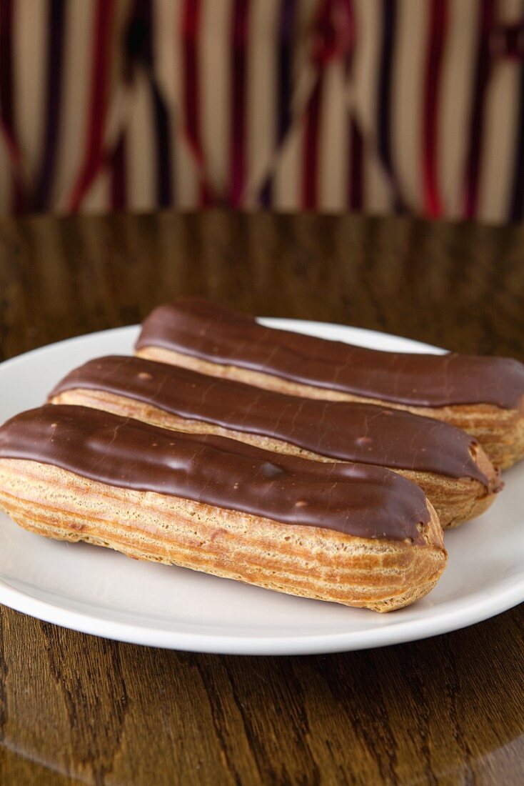 Three Chocolate Eclairs on a White Plate
