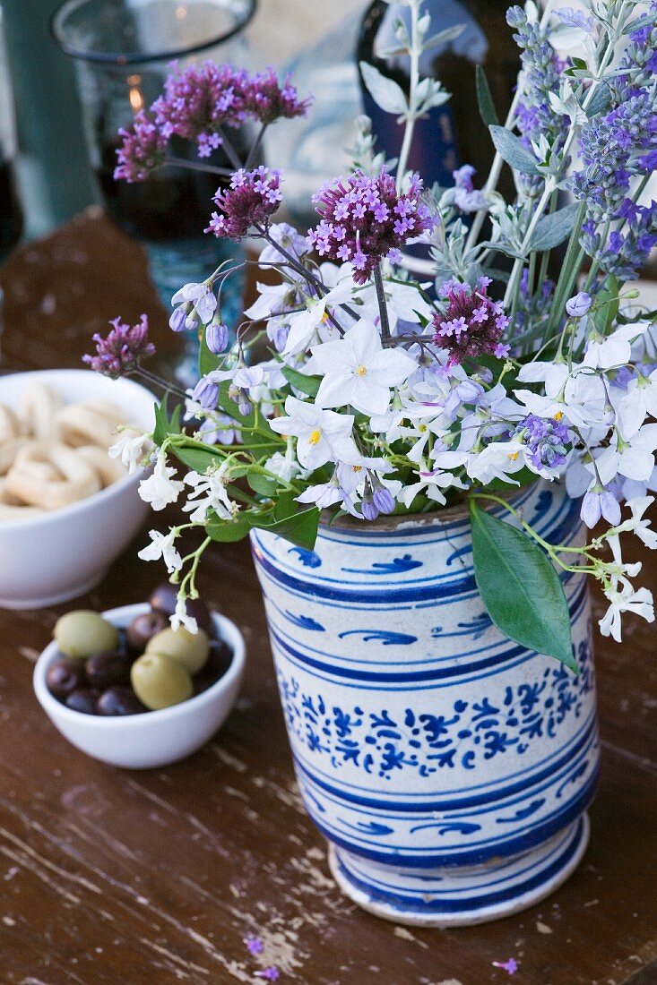 Garden flowers in painted ceramic vase on wooden table