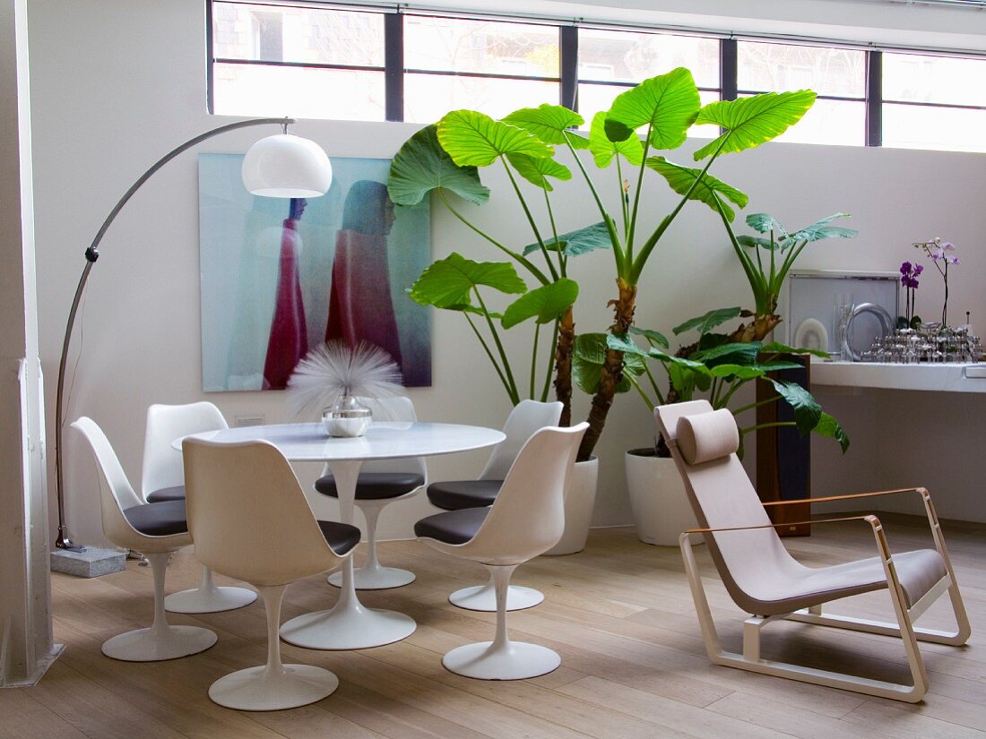 White shell chairs at round table and arc lamp in corner of loft apartment