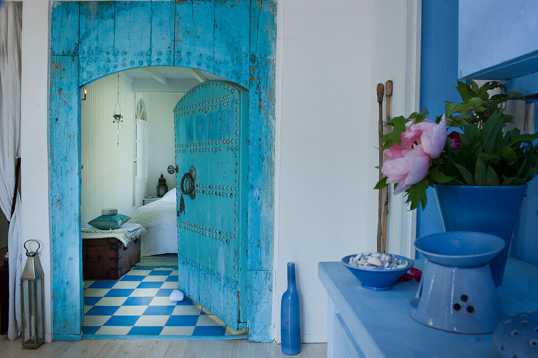 Blick in Schlafzimmer, blaue Holztür im orientalischen Stil, blau-weiß karierter Boden