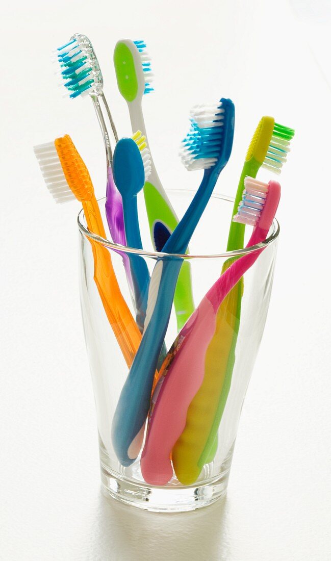 Assorted Colorful Toothbrushes in a Glass; White Background