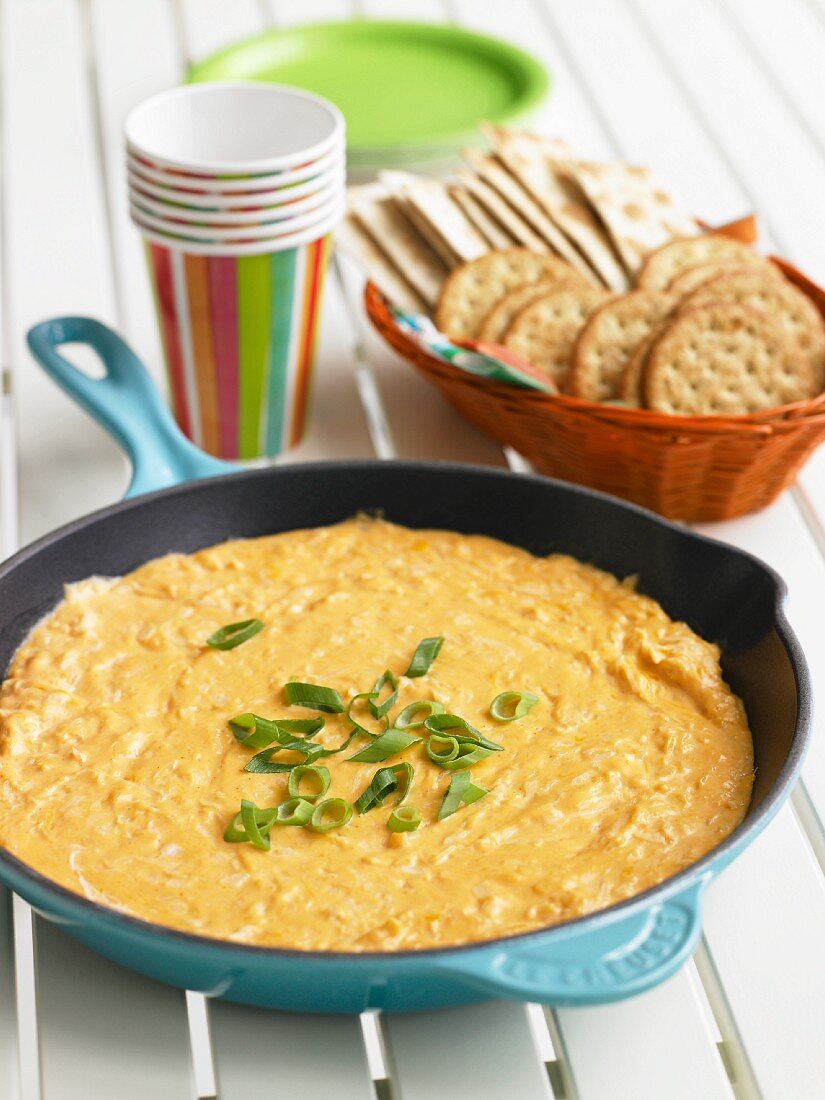 Mexican Cheese Dip in a Skillet with a Basket of Crackers