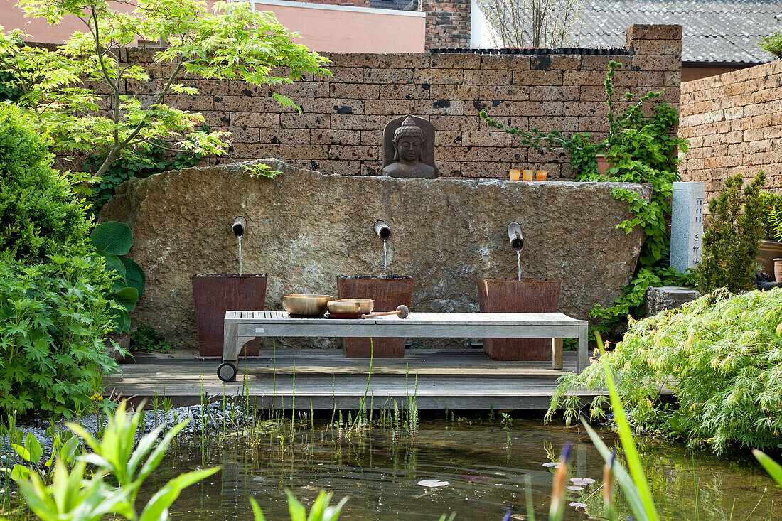 Asiatisch inspirierter Garten mit Wasserbecken und Buddha-Statue