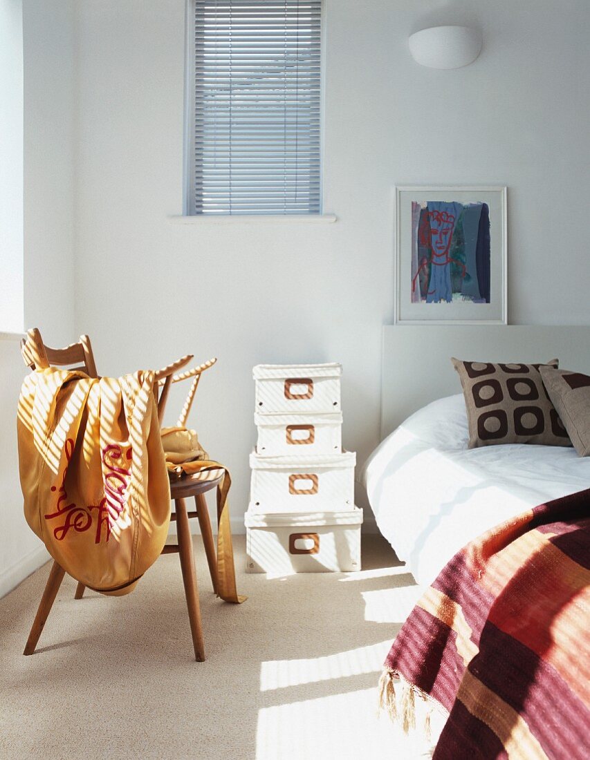 Blanket on chair and stack of boxes next to bed