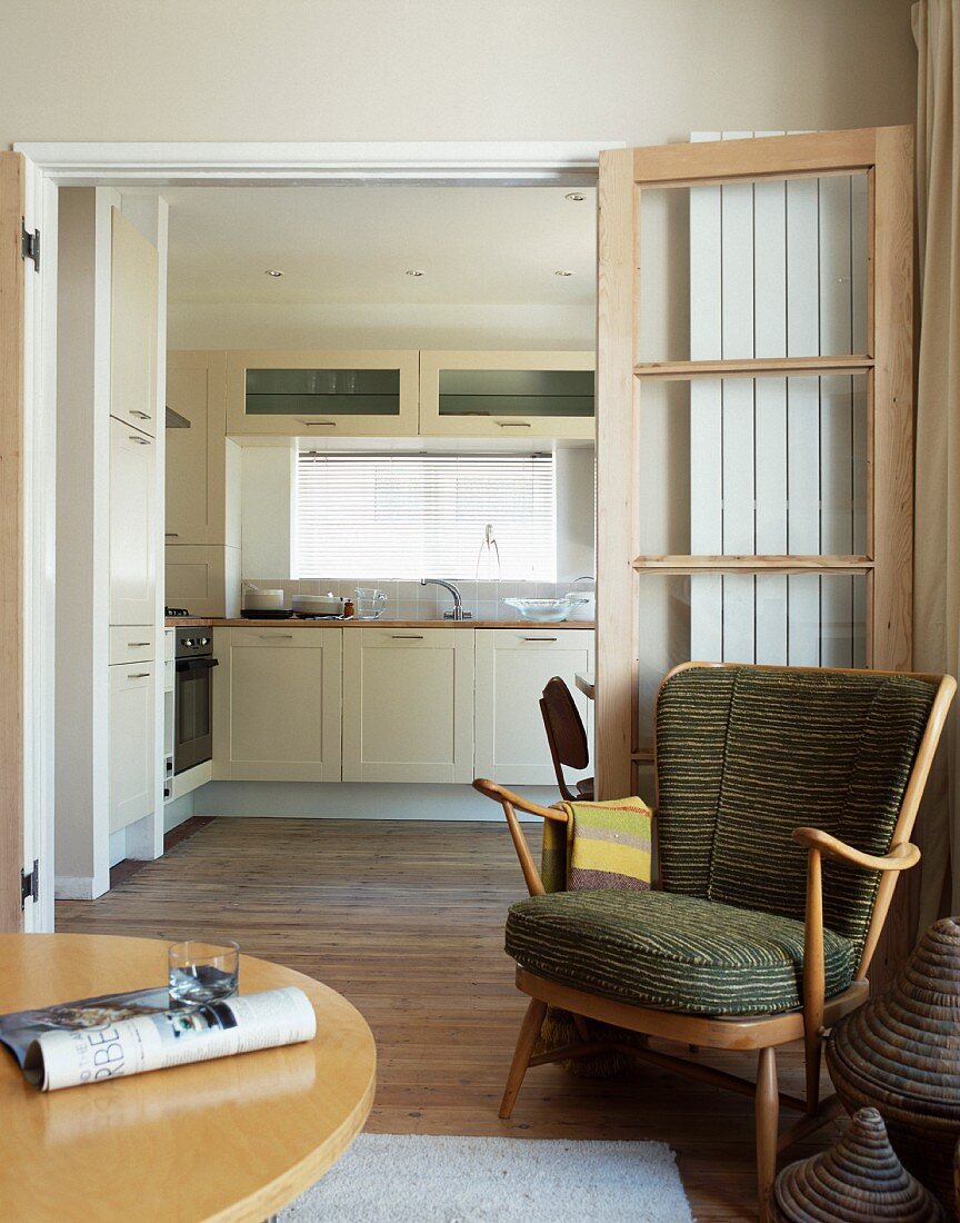 50s-style armchair in front of open double door with view of modern kitchen