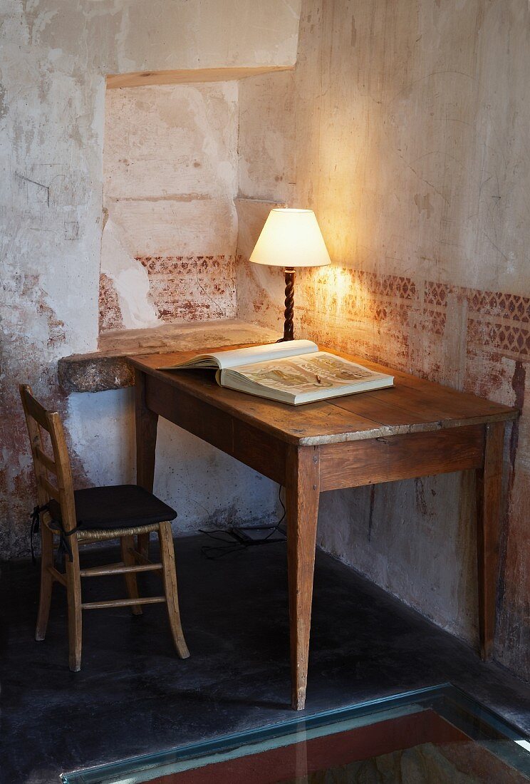 Tischlampe auf Holztisch vor Wand mit verblasster Schablonenmalerei