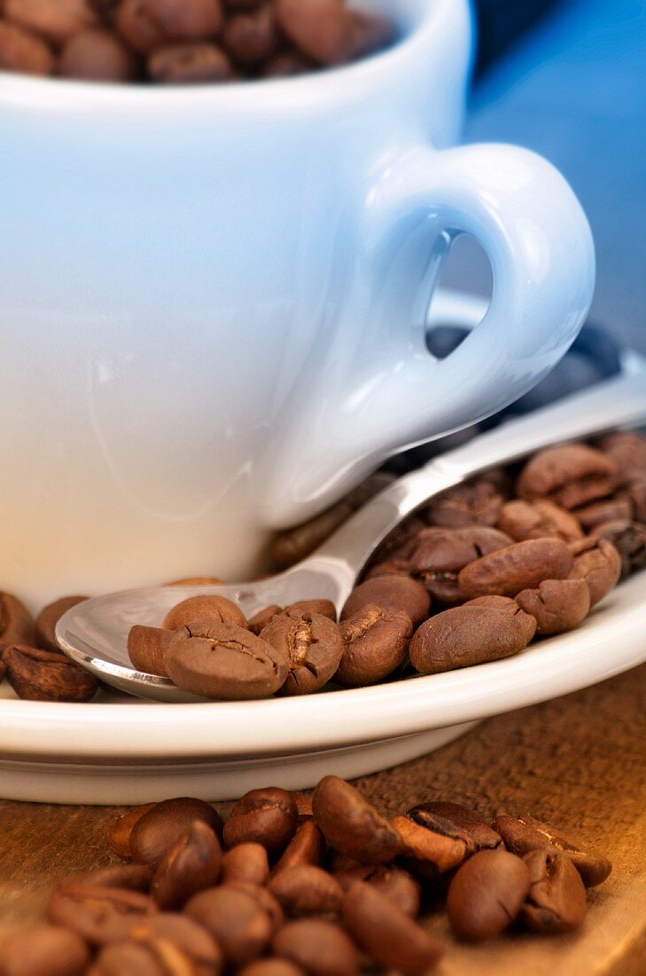 Coffee beans in and around coffee cup and saucer