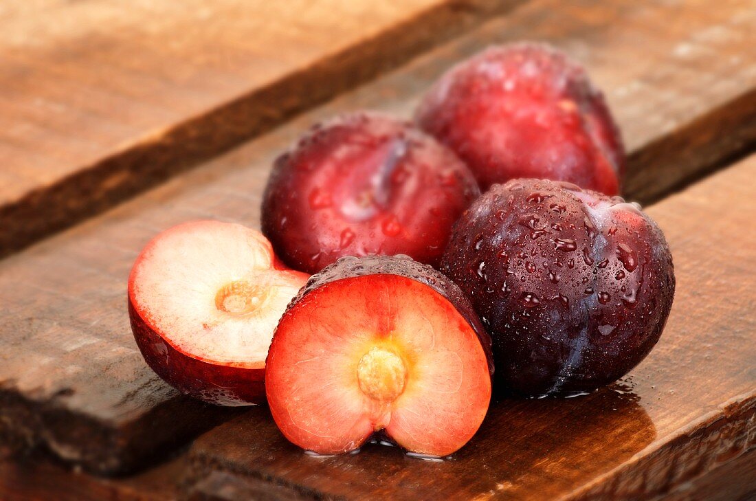 Plums, whole and halved, on wooden crate