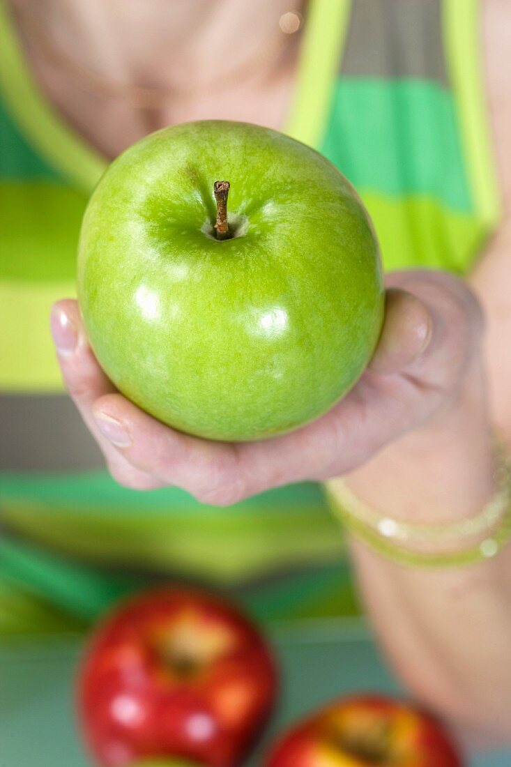 A woman holding a green apple